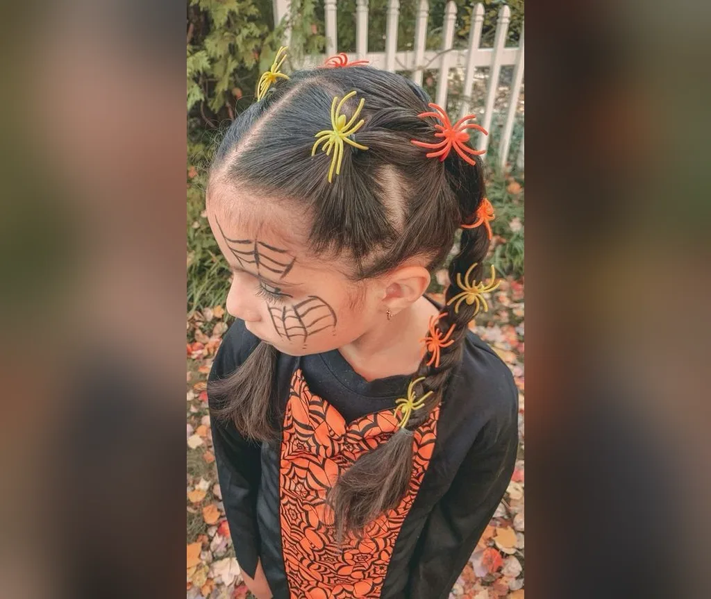 Side view of braided pigtails decorated with colourful spider clips and web face paint, halloween hairstyles for girls