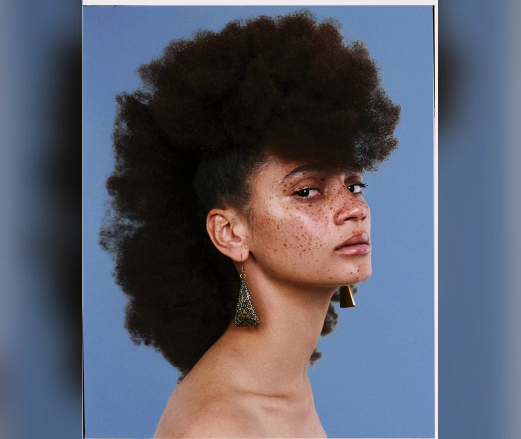 Afro mohawk on a Black woman against a blue background