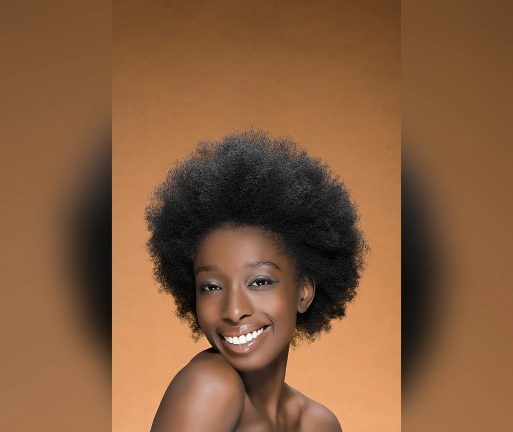 Joyful short afro on a smiling Black woman against an orange background