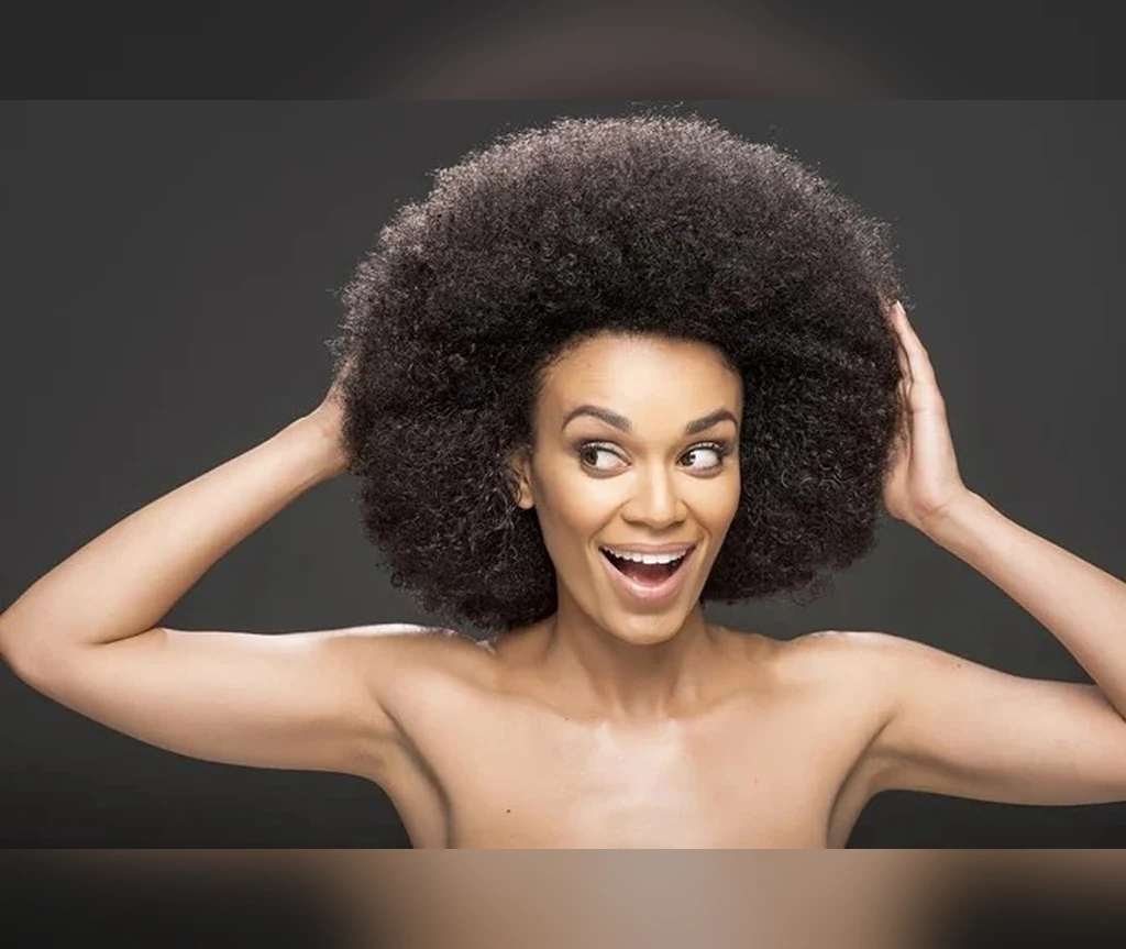 Voluminous short afro on a smiling Black woman with hands in her hair