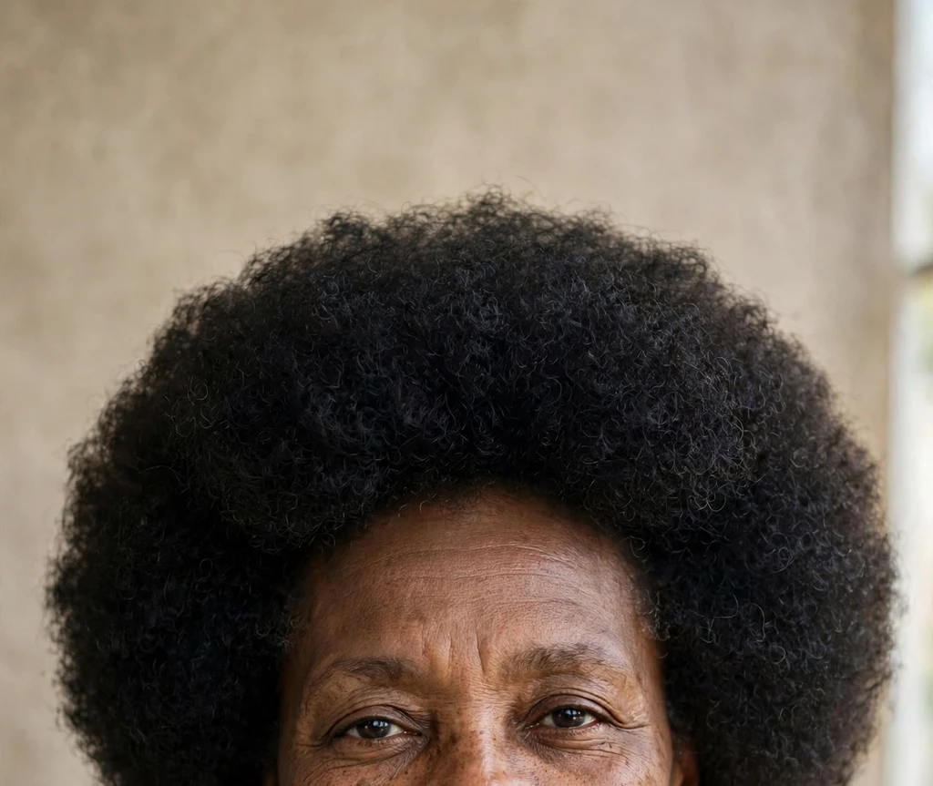 Black woman in her fifties with a dense 4C short afro, gold top, studio portrait